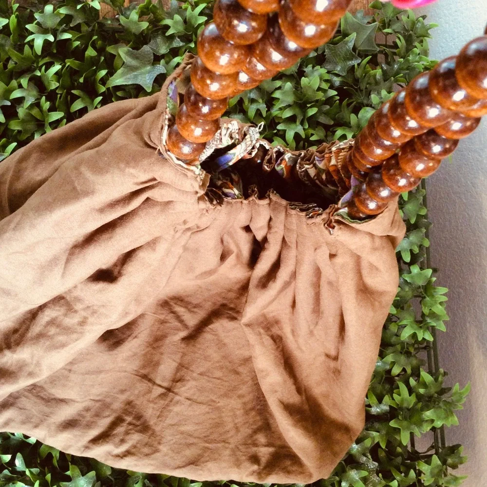 Reversible hobo tote with brown wood balls straps. Has a tie strap closu…